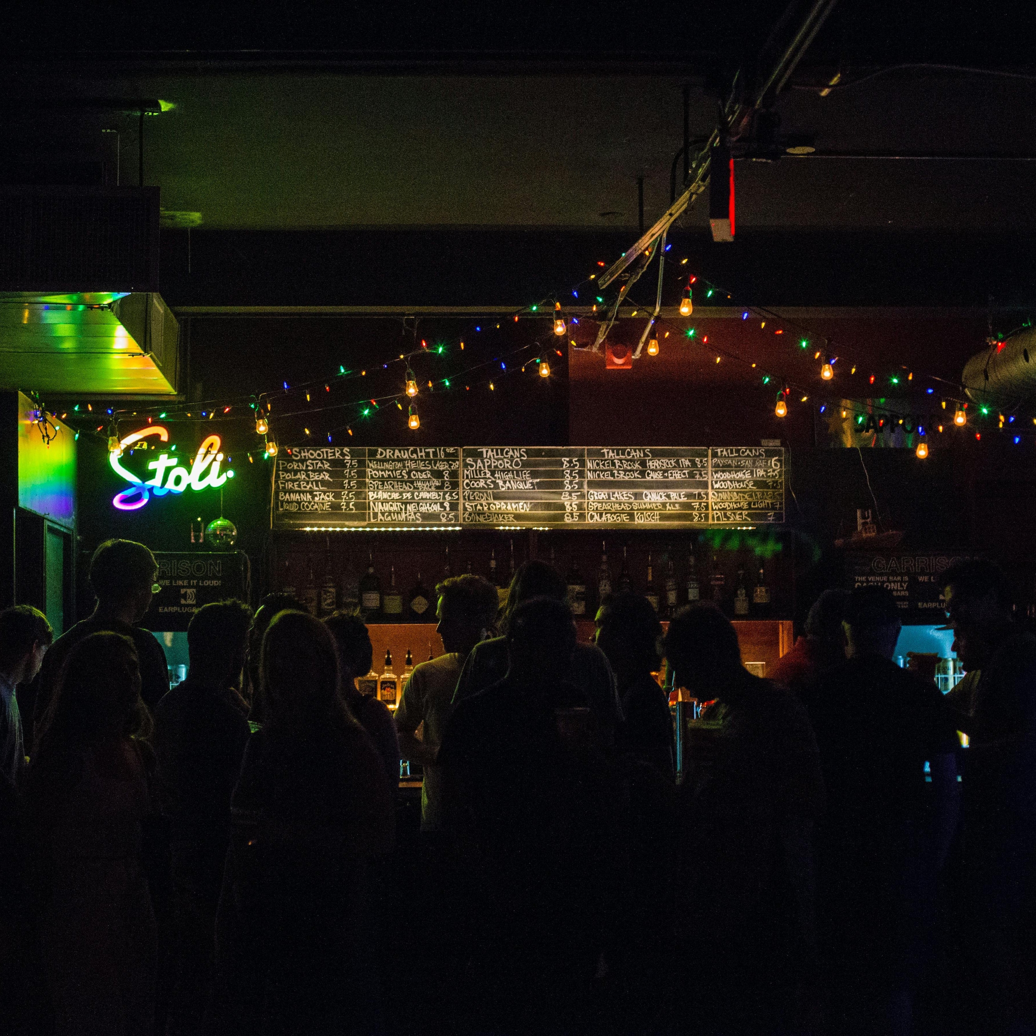 People gathered at a lively bar with colorful string lights, creating a festive night-out atmosphere.