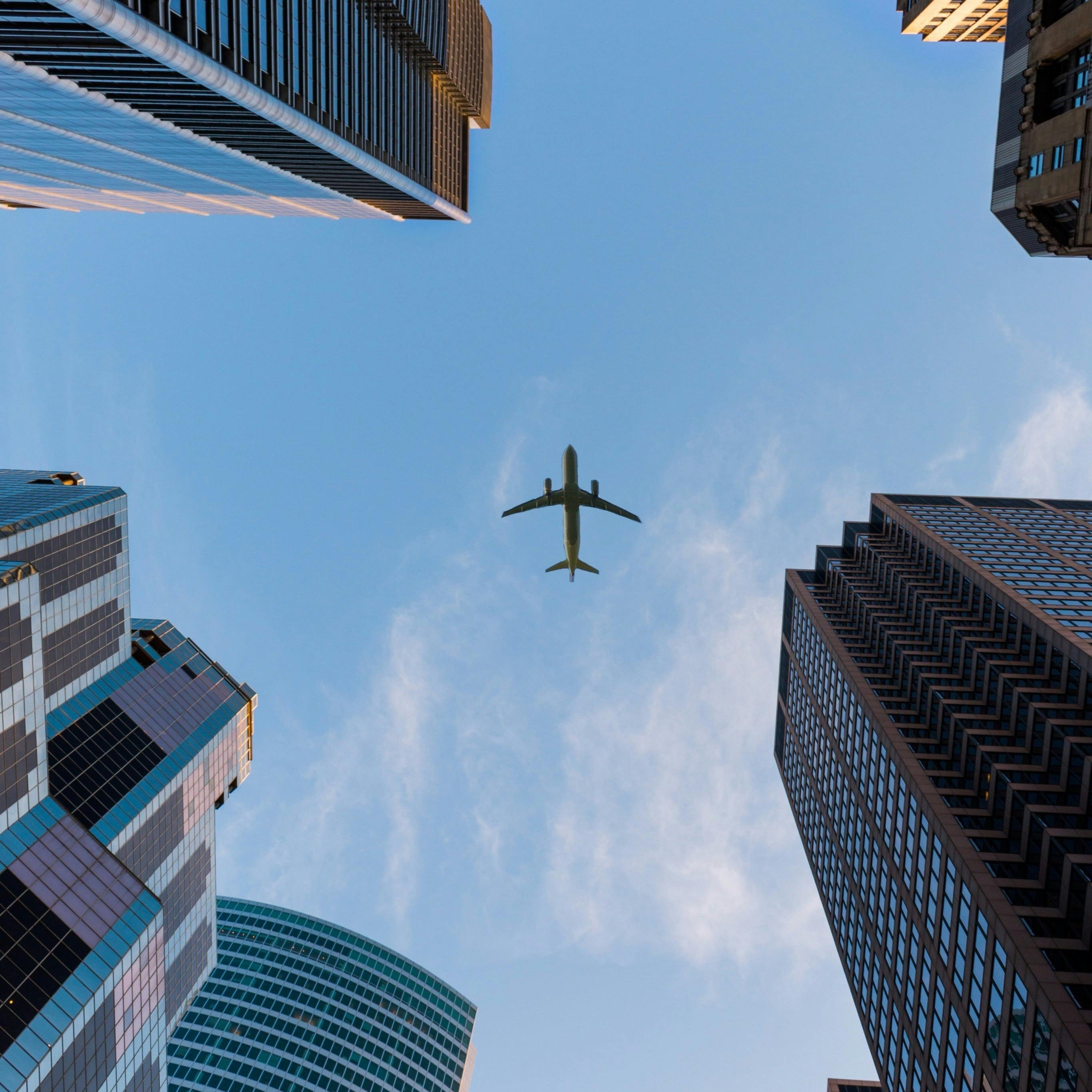 Airplane flying above skyscrapers, symbolizing travel, exploration, and adventure in the city and beyond.