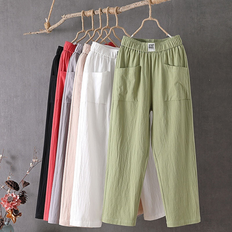 Green pants hanging on a rack with other colors against a gray background