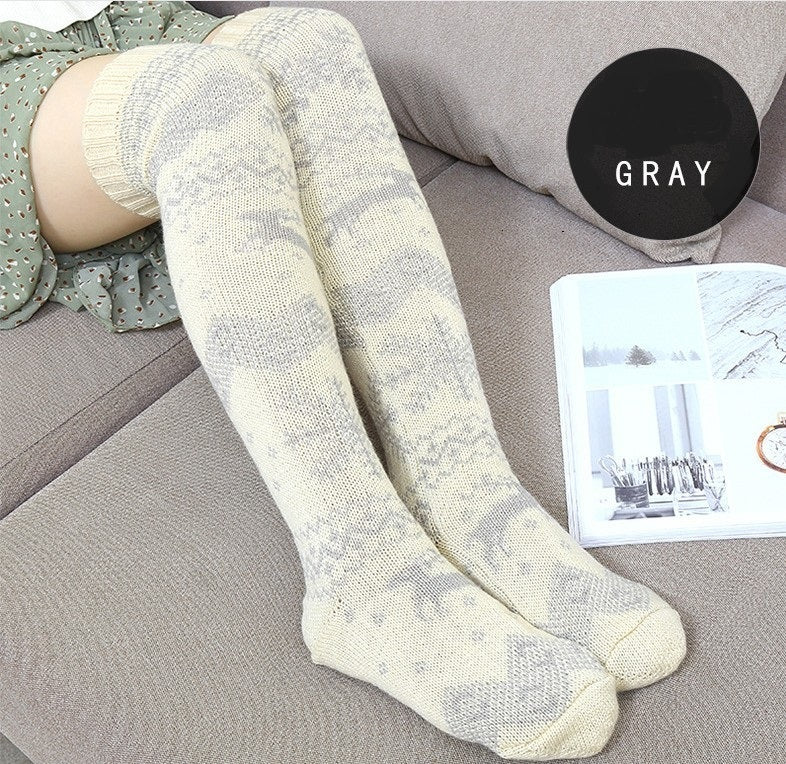 Person wearing white knee-high socks on a gray couch with a magazine and 'GRAY' sign.