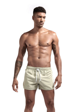 Man wearing light-colored swim shorts on a white background