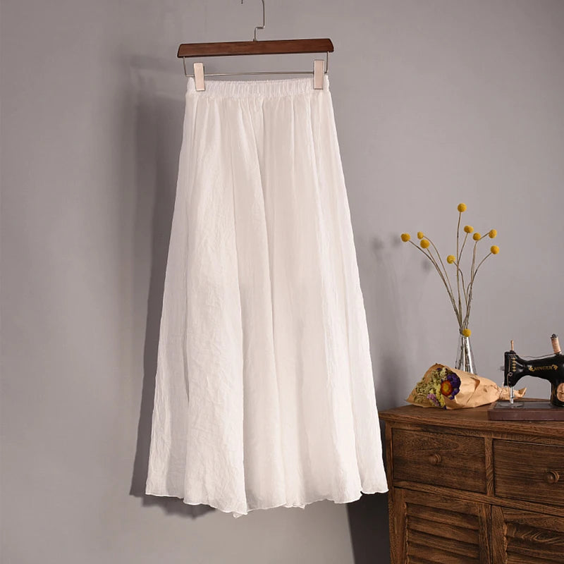 White skirt hanging on a wooden hanger against a gray wall with a wooden dresser and decorative items in the background.
