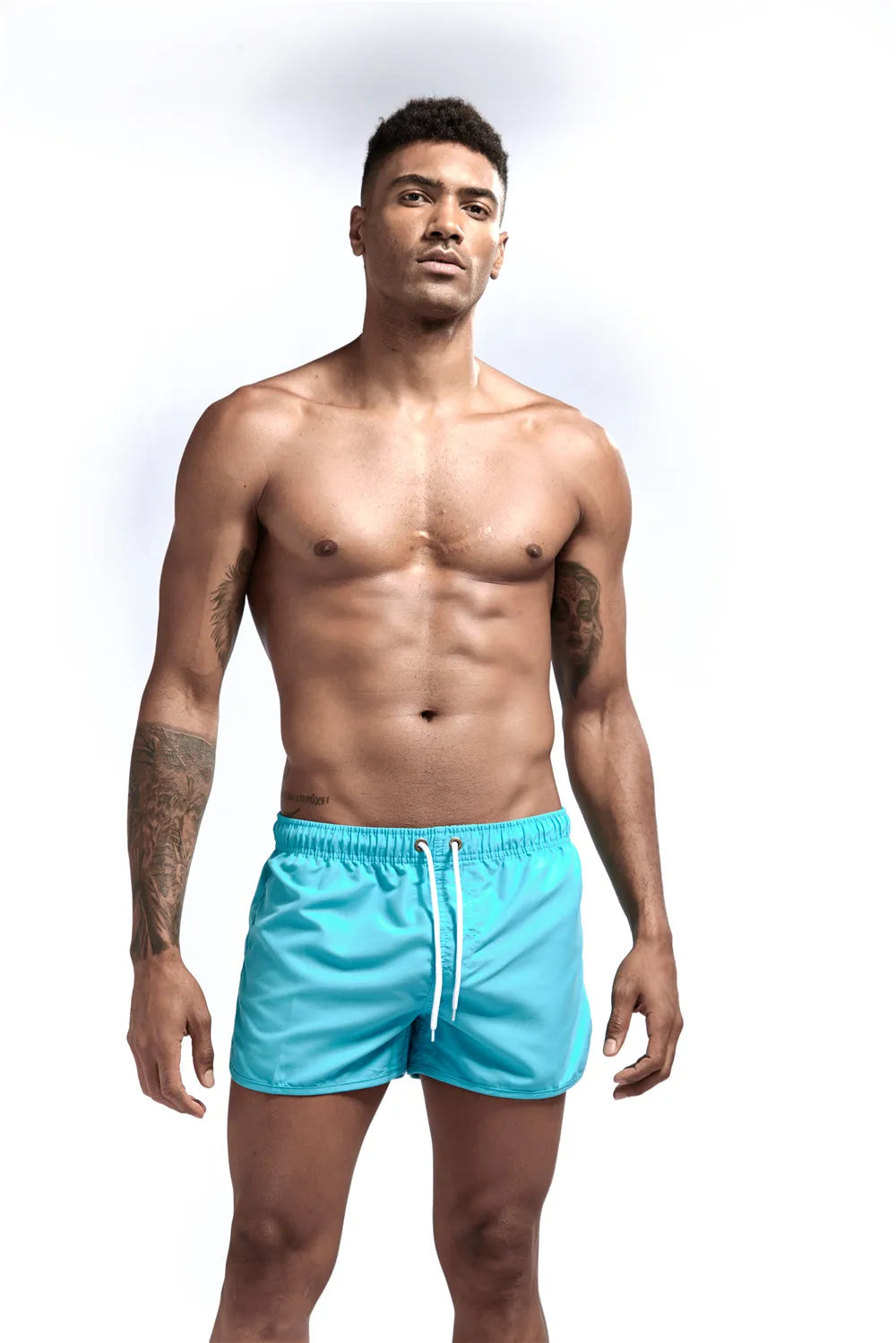 Man wearing turquoise swim shorts on a white background