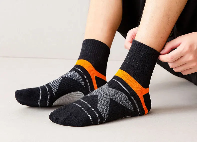 Person wearing black socks with orange accents on a light background