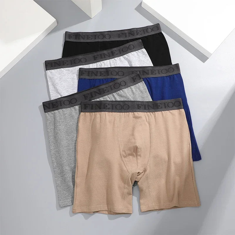 Set of men’s cotton boxer briefs in blue, black, gray, khaki, and light grey on a flat background