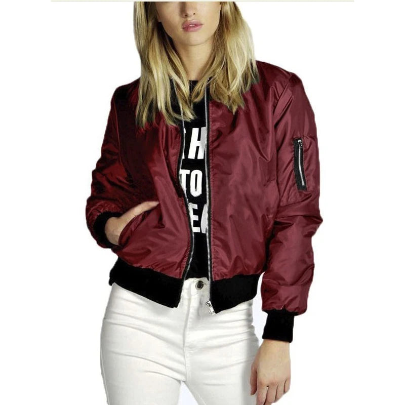 Woman wearing a wine-red bomber jacket with zip front, ribbed cuffs and hem, styled with white pants.