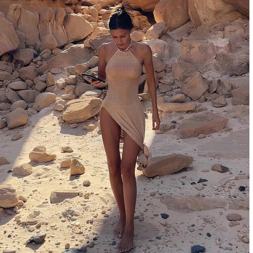 Woman in a beige dress standing on a rocky beach