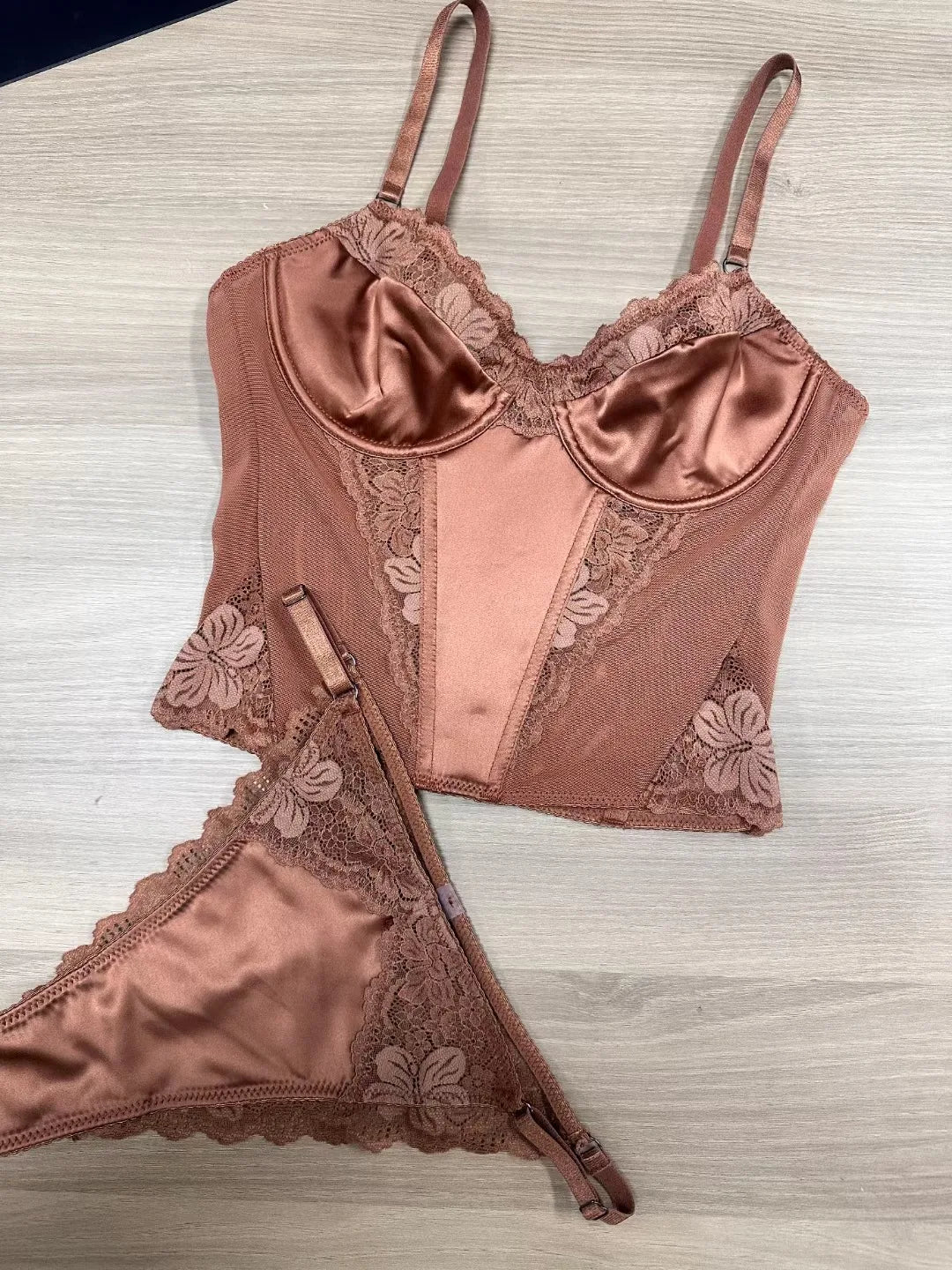Rose gold lingerie set with lace details on a light wooden surface