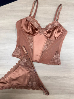 Rose gold lingerie set with lace details on a light wooden surface