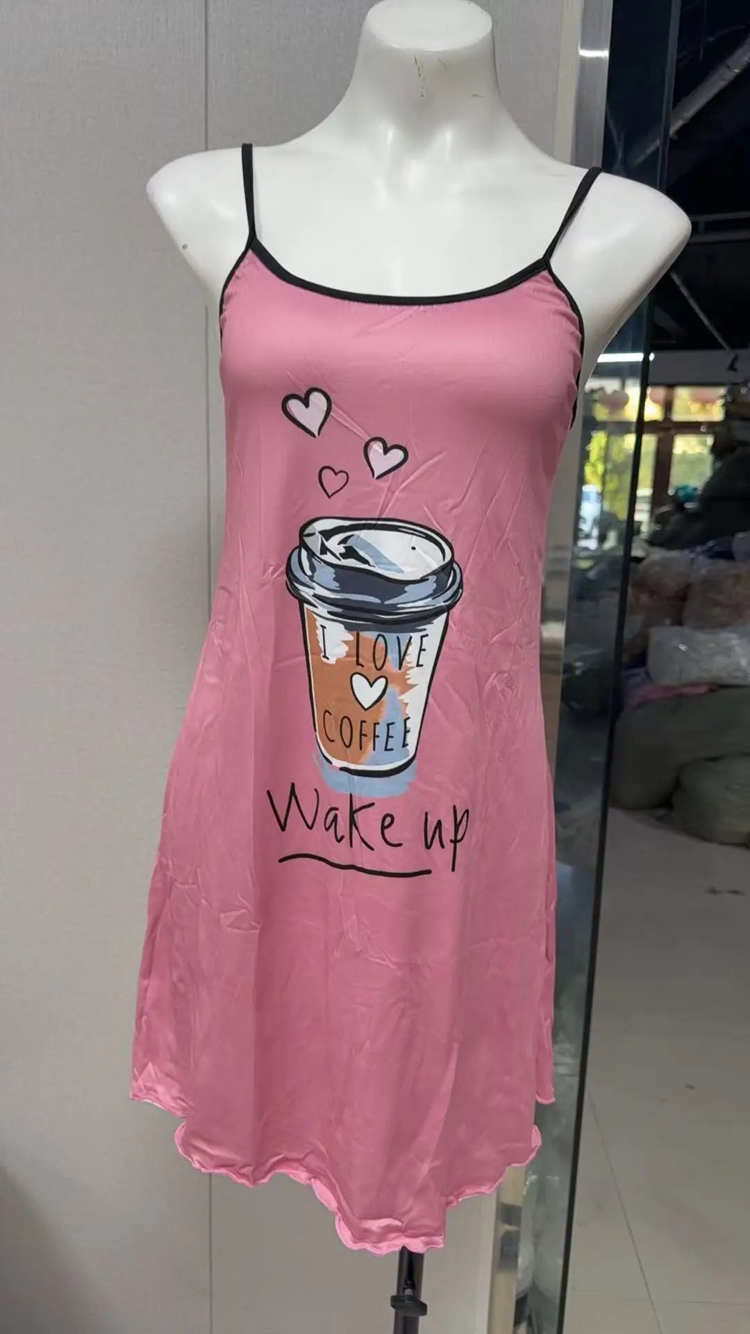 Pink nightgown with coffee cup design on a mannequin against a neutral background