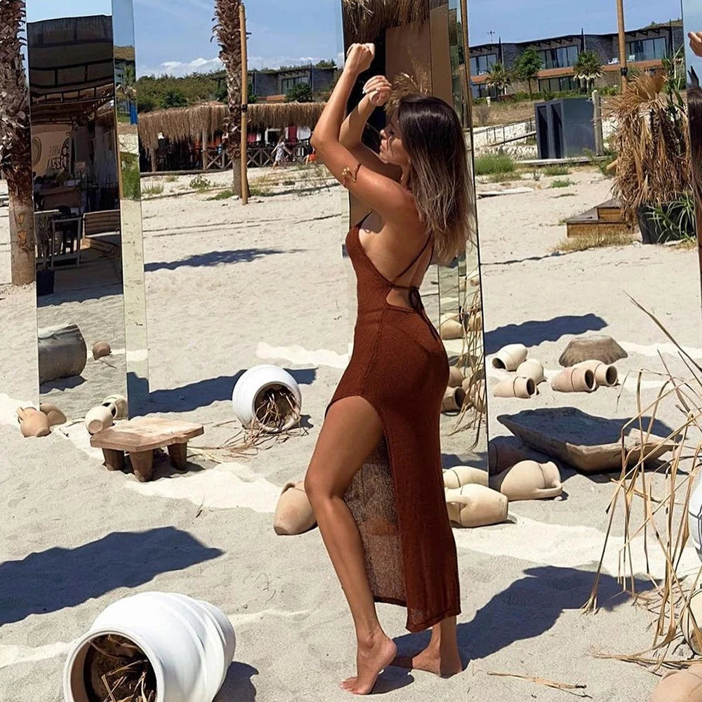 Woman in a brown dress standing in a sandy outdoor area with rustic decor.