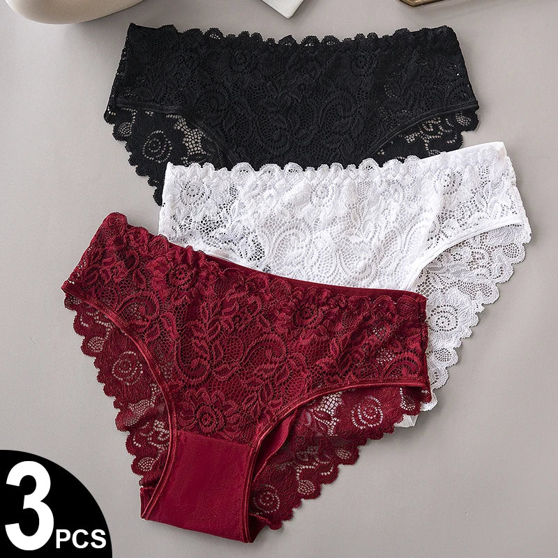 Three pairs of lace underwear in black, white, and red on a gray surface.
