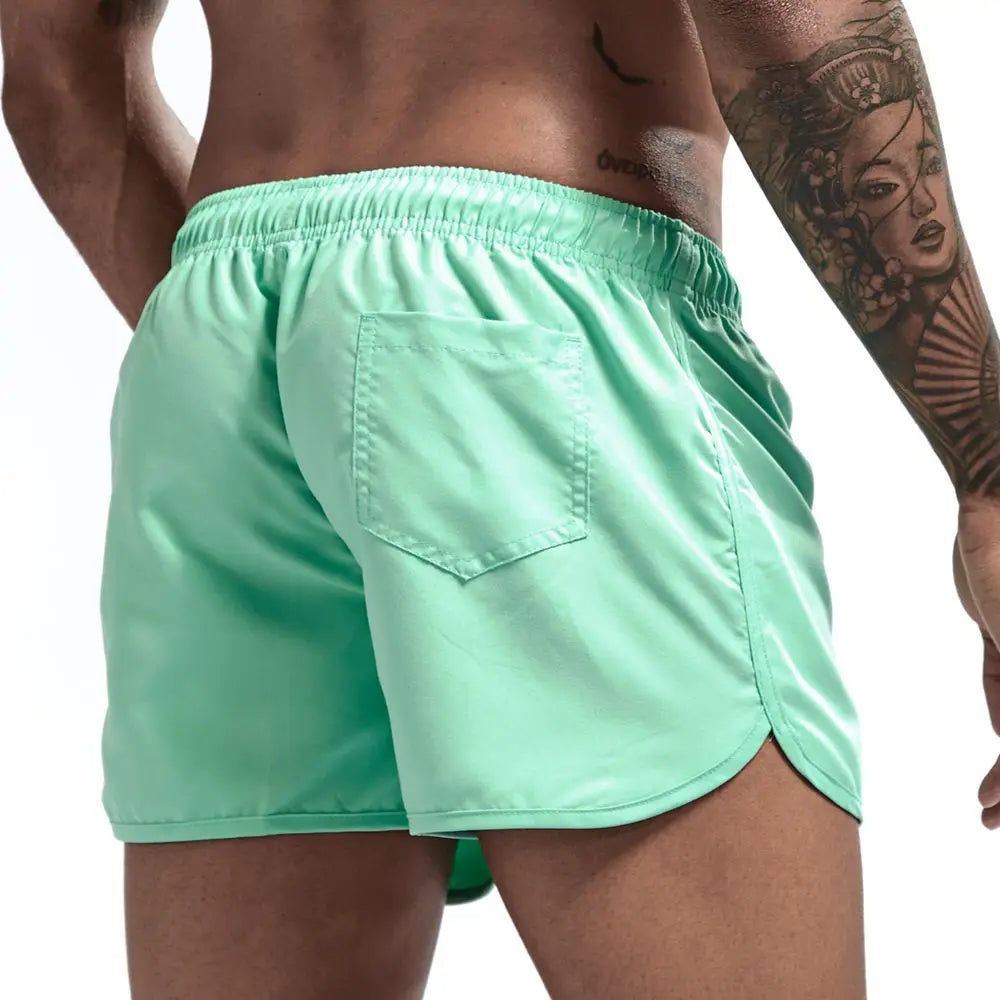Mint green swim shorts worn by a person on a white background