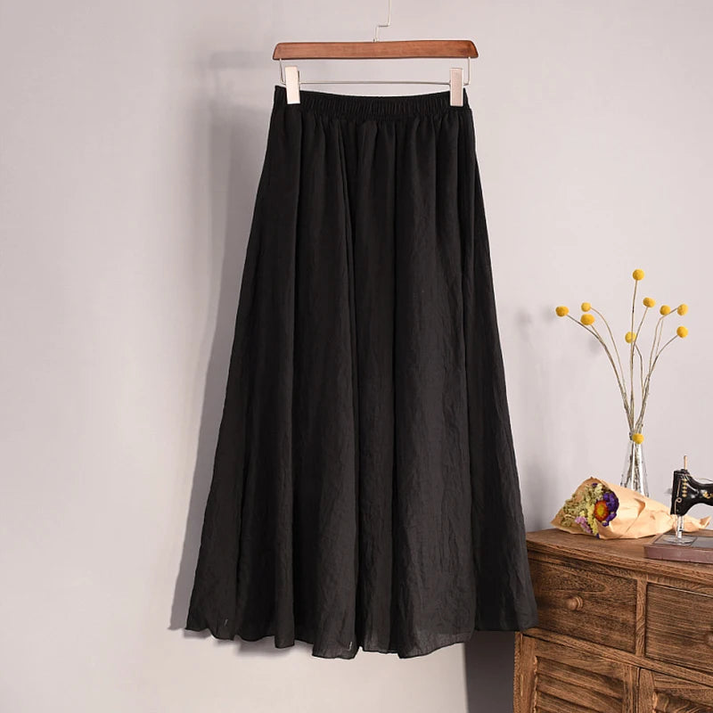 Black skirt on a hanger against a plain wall with a wooden dresser and decorative items in the background.