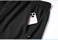 Black pants with a phone peeking out from a pocket on a white background