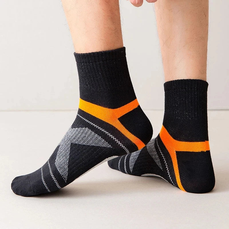 Black socks with orange accents worn by a person on a light background