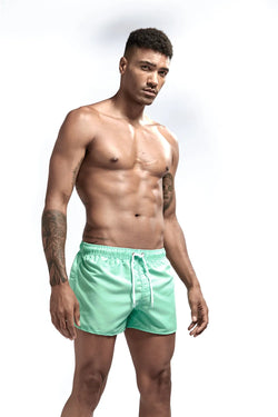 Man wearing light green swim shorts on a white background