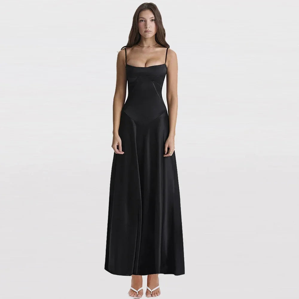 Woman in a black satin spaghetti-strap maxi dress on a light gray background.