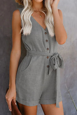 Woman wearing a gray romper with a belt against a neutral background