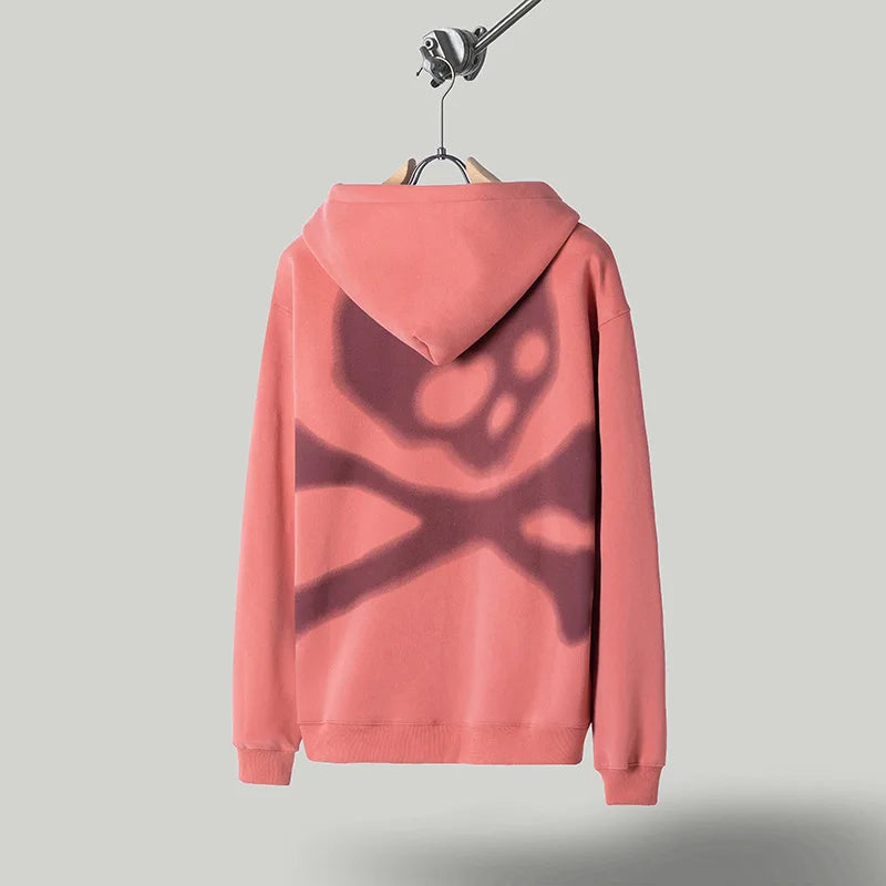 Pink hoodie with a dark design on the back, hanging against a gray background