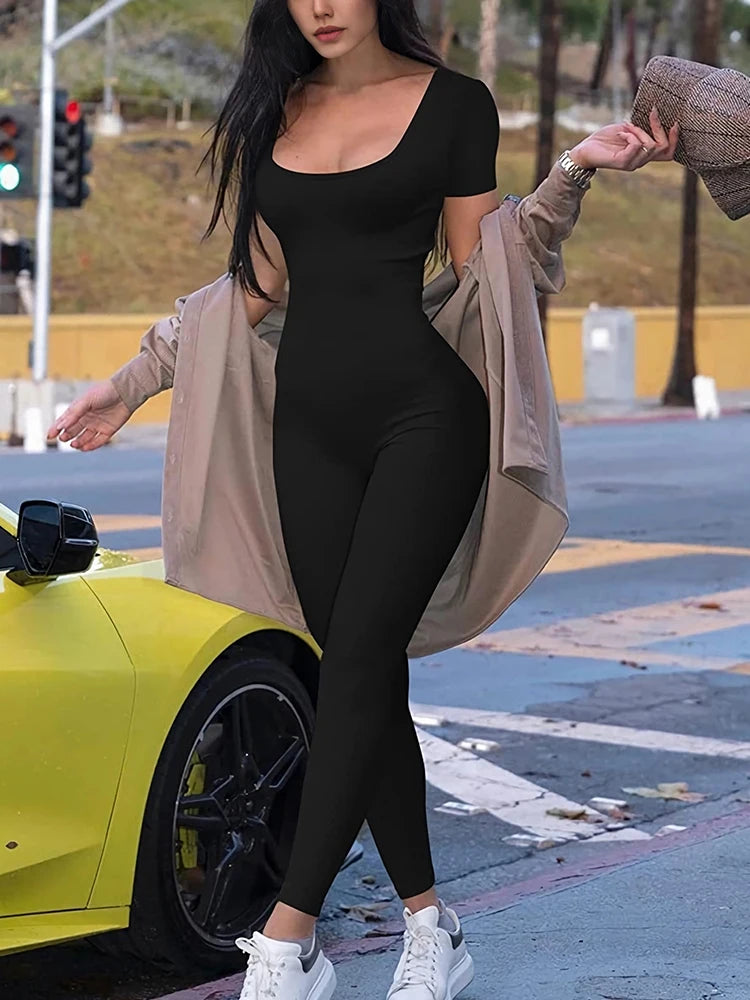 Woman in black outfit standing next to a yellow car on a street.