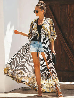 A woman wearing a leopard print bikini cover up with long sleeves, styled over denim shorts.
