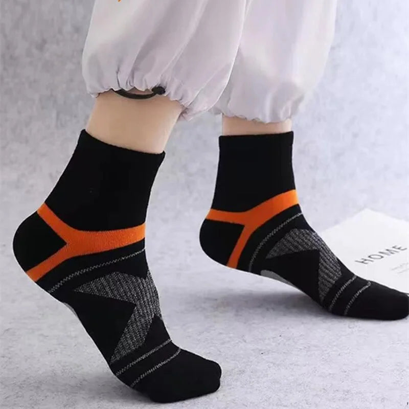Black socks with orange accents worn by a person on a light gray background