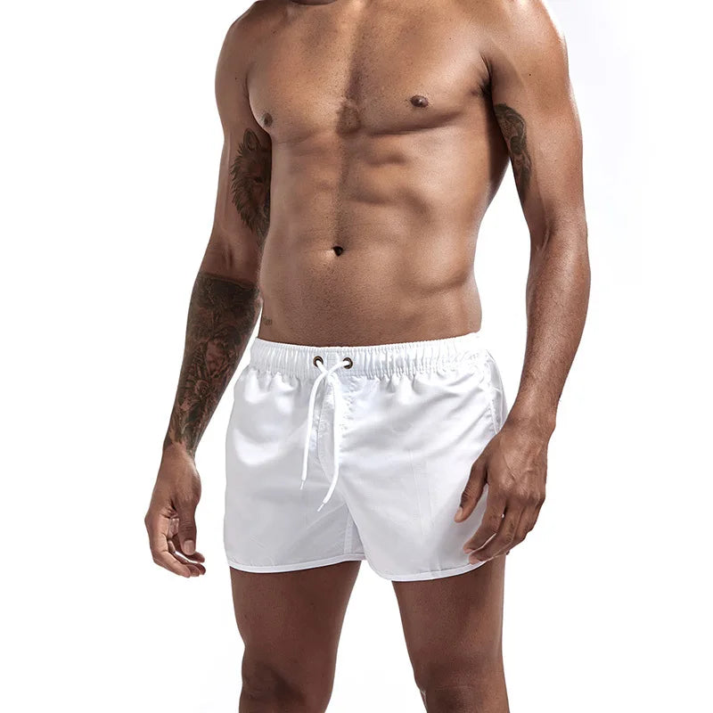 Man wearing white swim shorts on a plain background