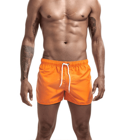 Man wearing bright orange swim shorts on a white background