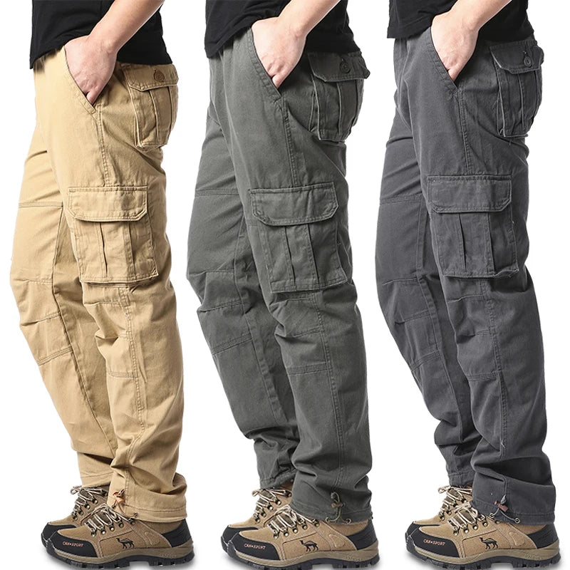 Three pairs of men's tactical cargo pants in beige, gray, and black colors, displayed side by side with a male model wearing a black T-shirt and brown boots.