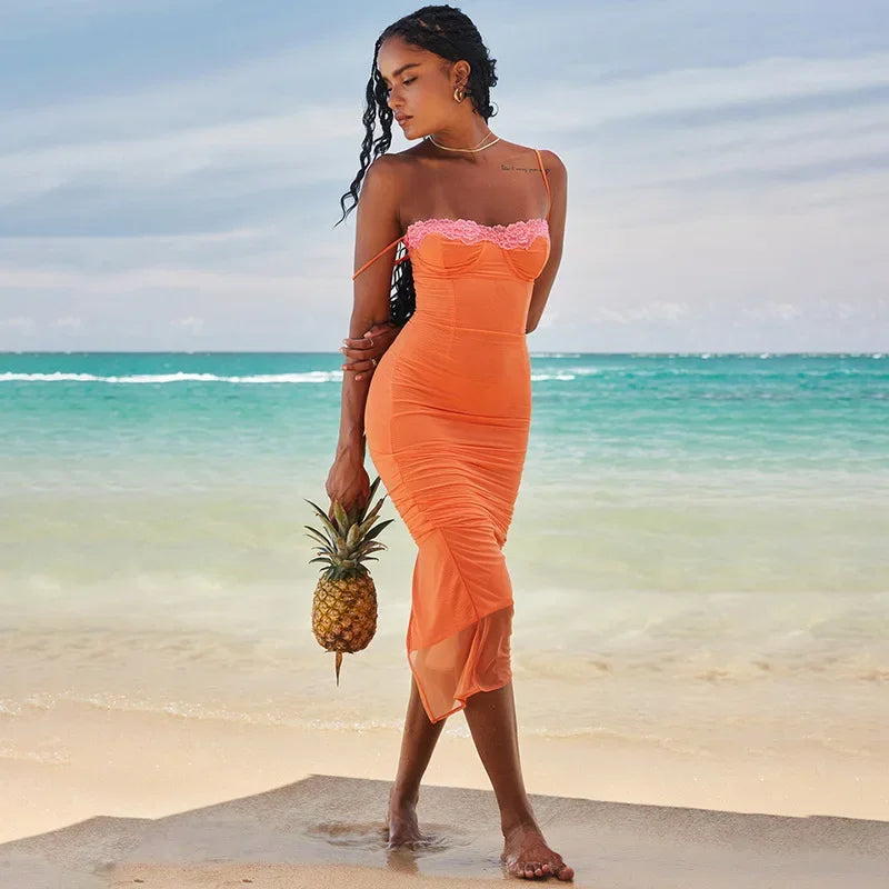 Woman in an orange dress holding a pineapple on a beach