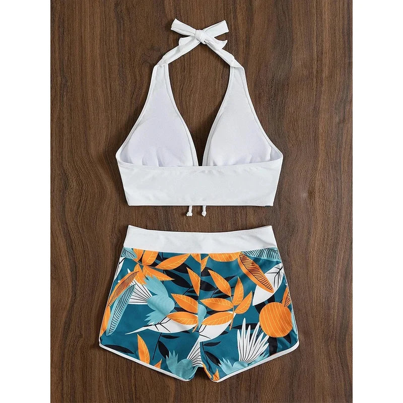 White bikini top and leaf-patterned shorts on a wooden surface