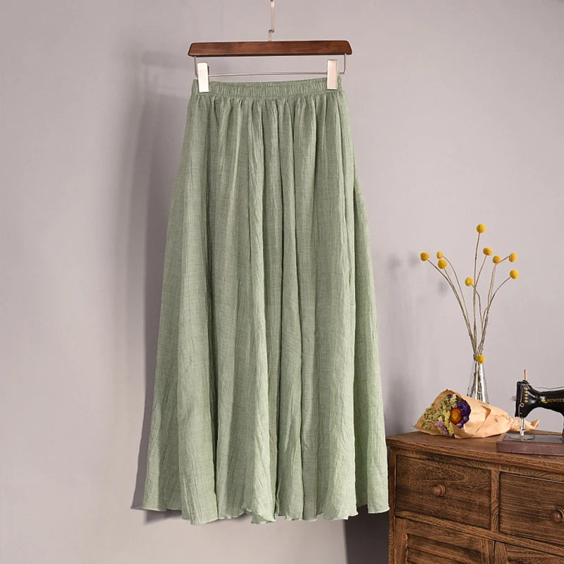 Green skirt hanging on a wooden hanger against a gray wall with a wooden dresser and decorative items in the background.