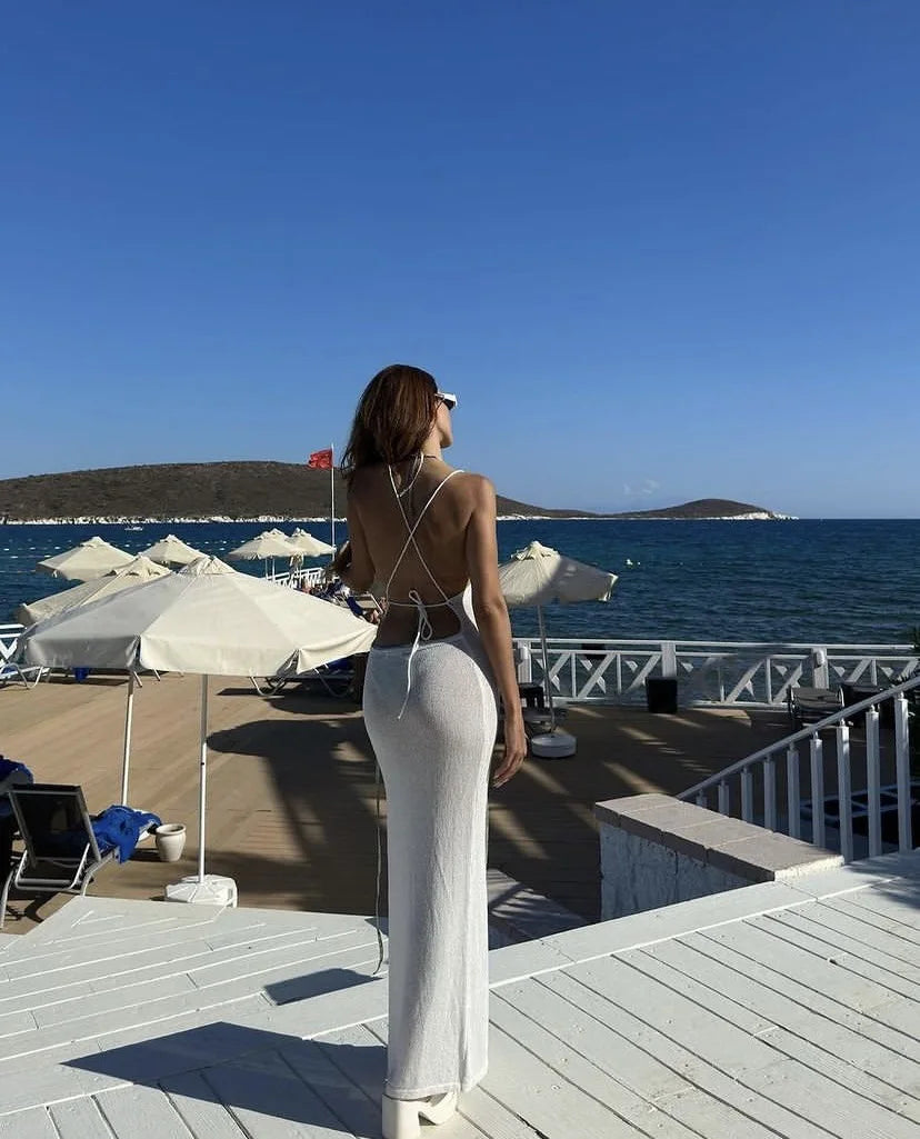 Woman standing on a deck overlooking the ocean with umbrellas and chairs.