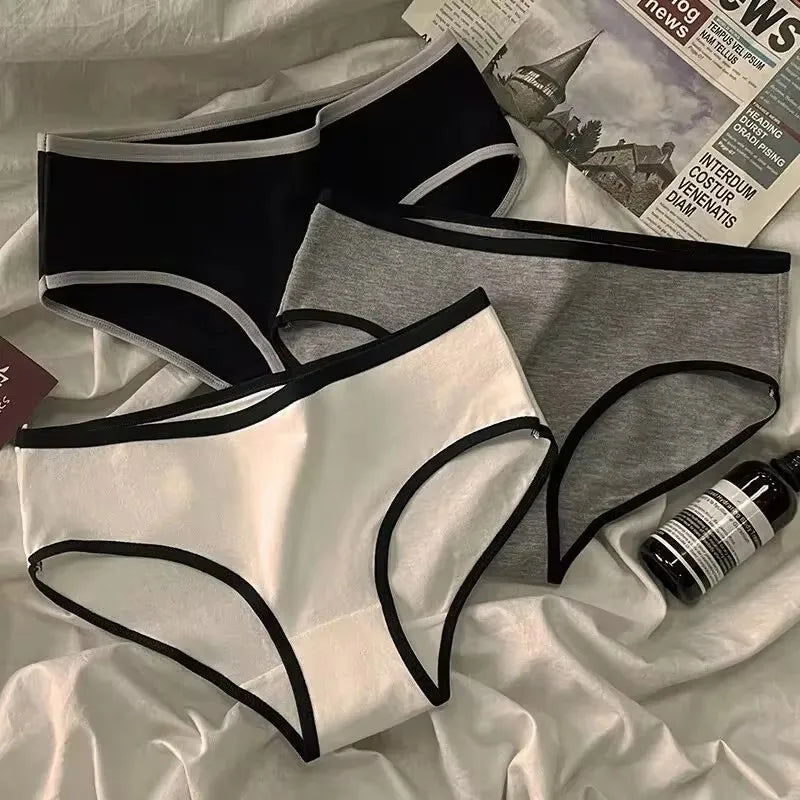 Black lace lingerie set on a white fabric background with a bottle and newspaper.