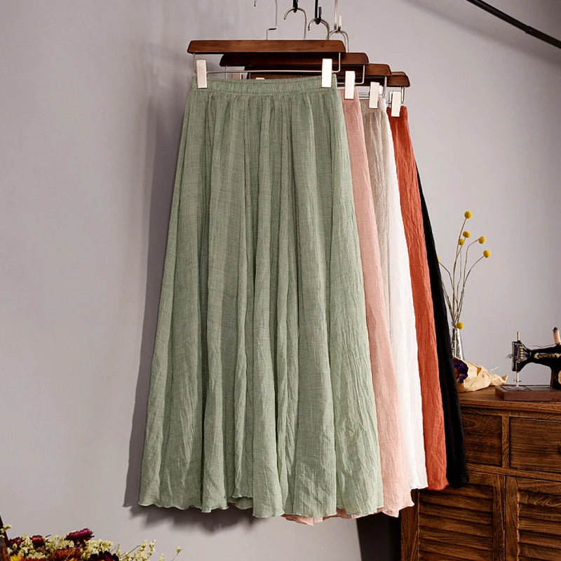 Green pleated skirt hanging on a wooden hanger against a gray wall with sewing machine and flowers in the background.