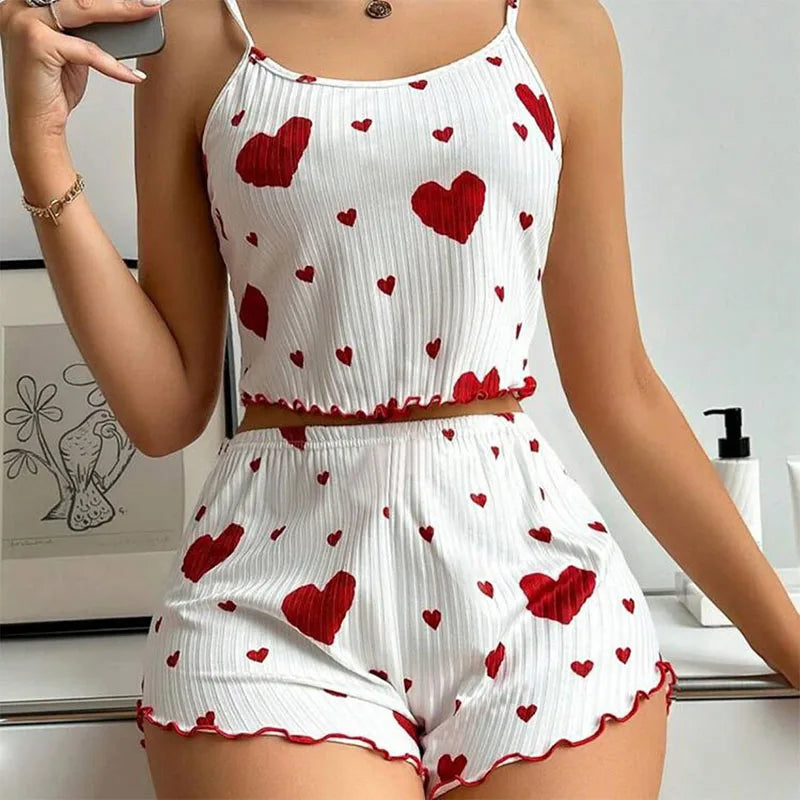 White romper with red heart patterns worn by a person, standing against a neutral background.