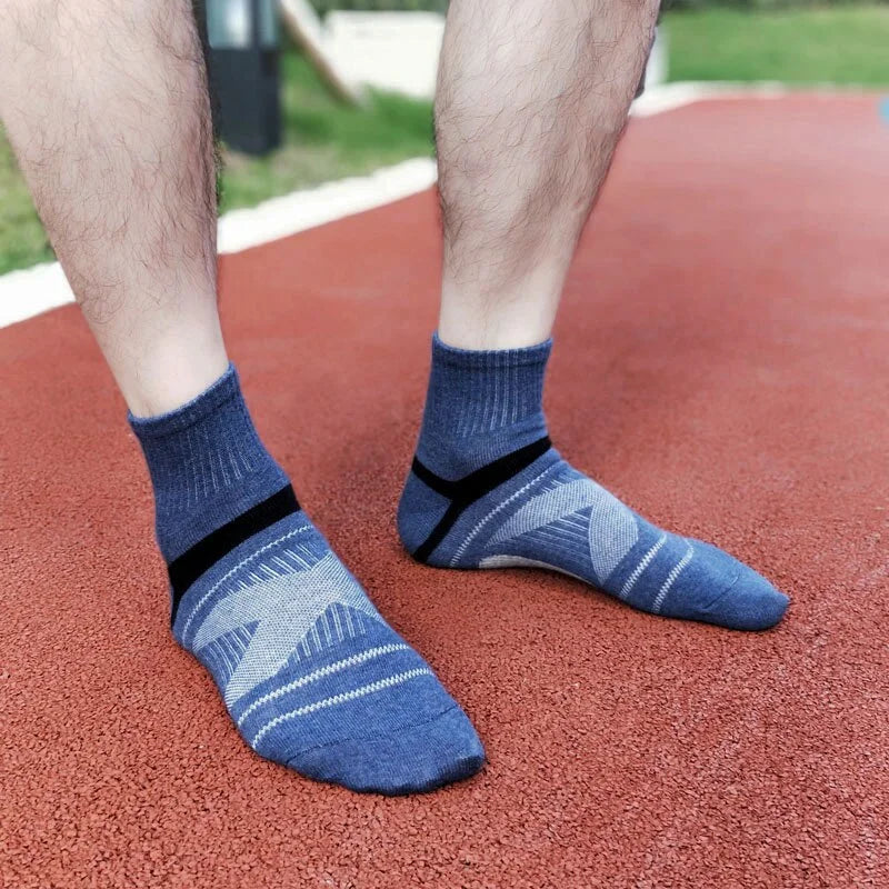 Blue socks with black stripes worn by a person on a red surface.