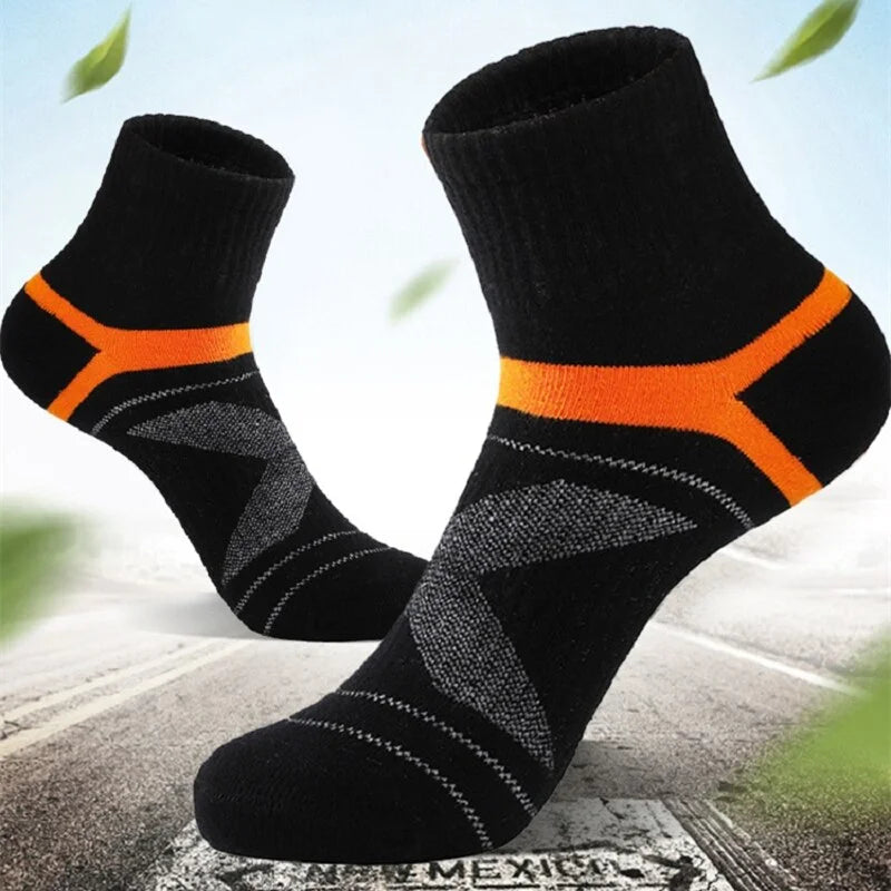 Black socks with orange accents on a textured surface with green leaves in the background