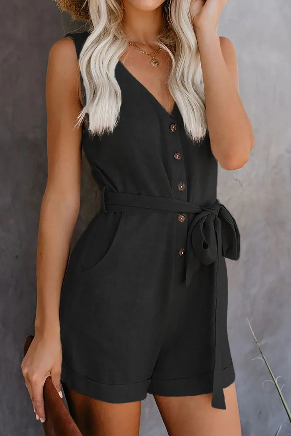 Woman wearing a black romper against a gray background