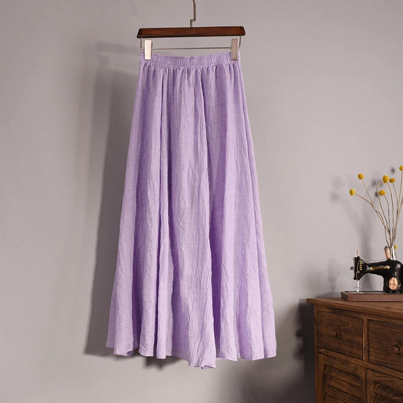 Purple skirt hanging on a wooden hanger against a gray wall with a sewing machine and vase in the background.