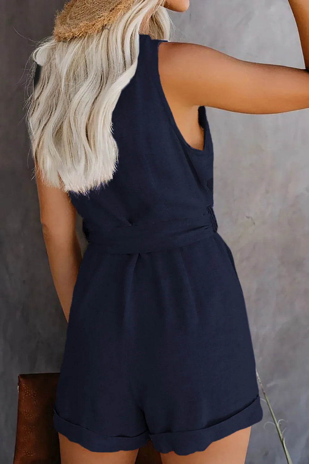Person wearing a navy blue romper against a neutral background