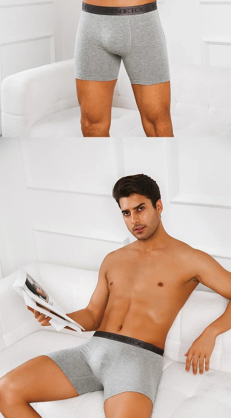 Man wearing gray boxer briefs sitting on a white couch with a newspaper.