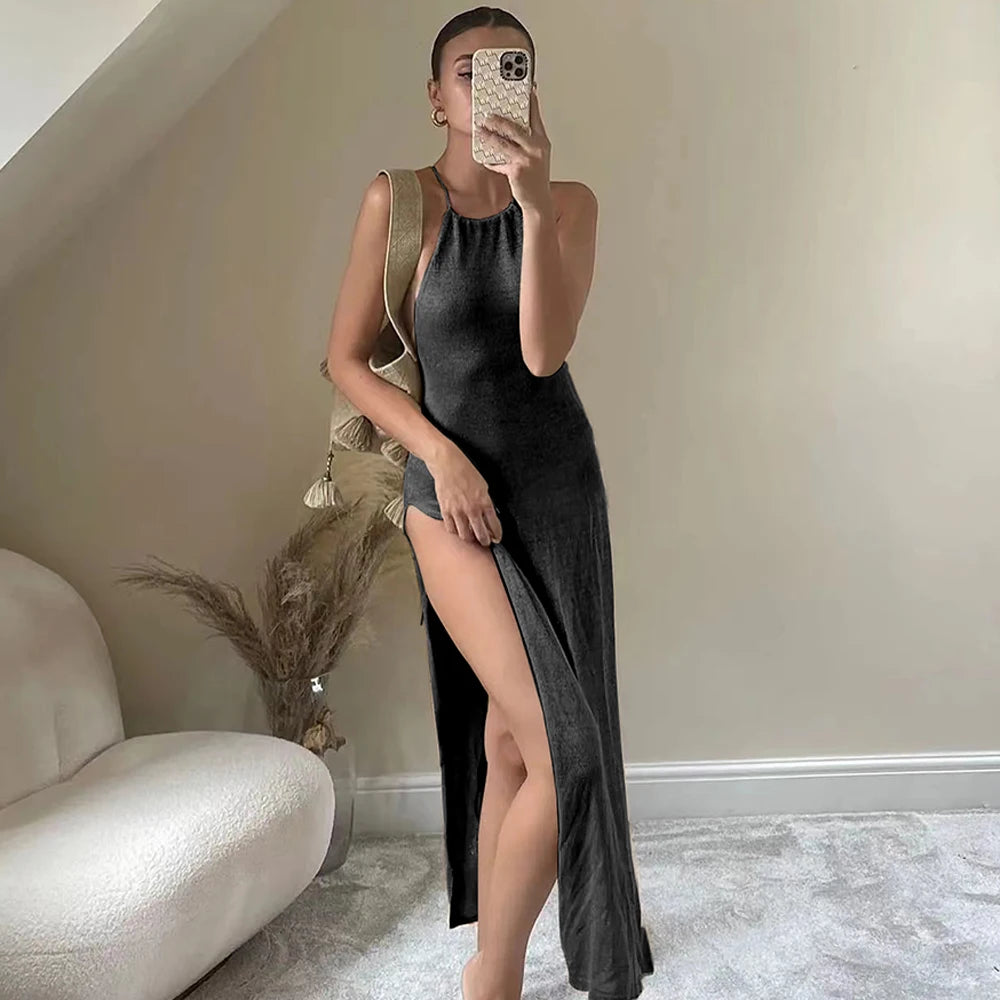 Person wearing a black sleeveless dress with a high slit, standing in a room with a neutral color scheme.